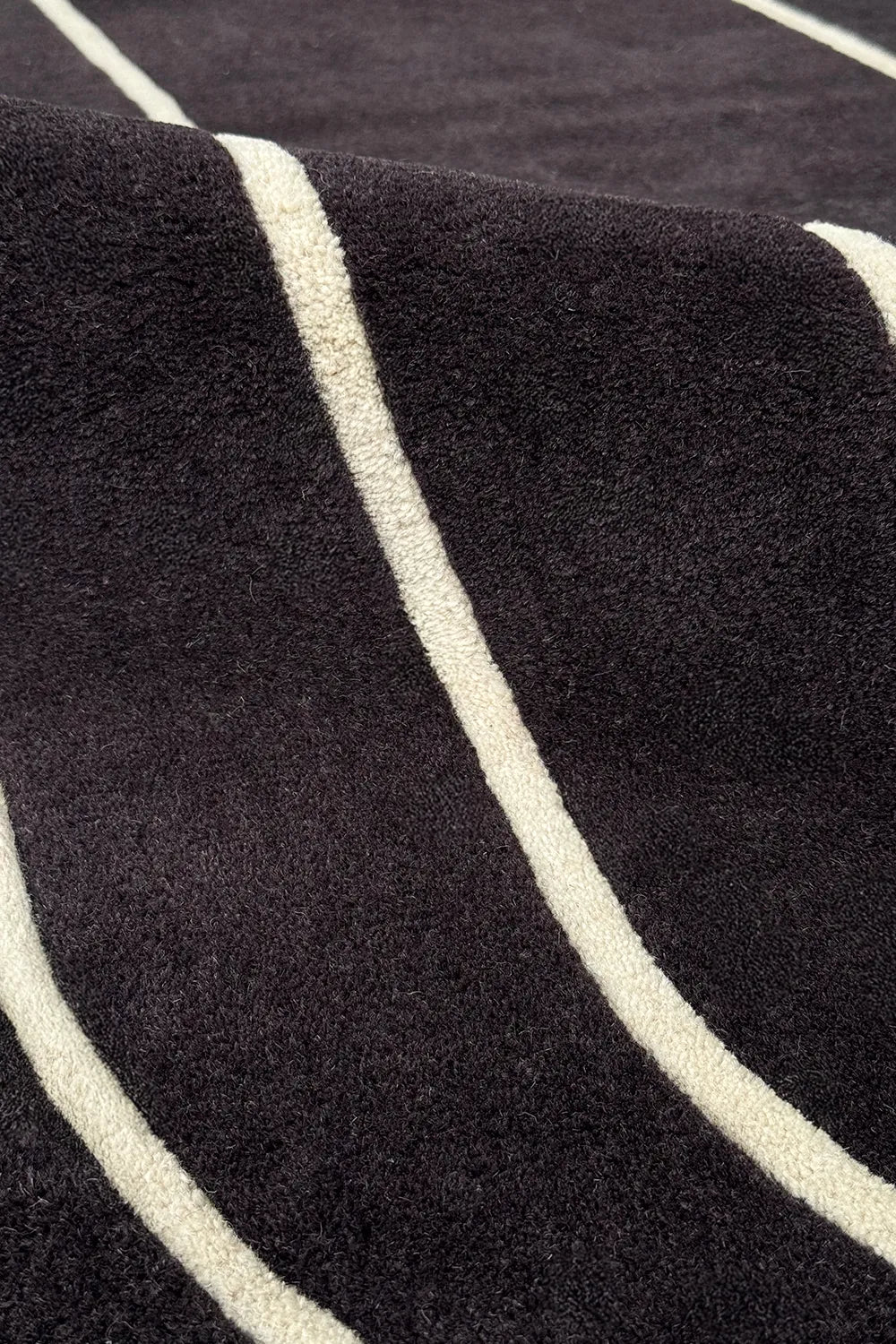 Close-up of geometric art deco rug – black and white wool area rug in a bold curved stripe design