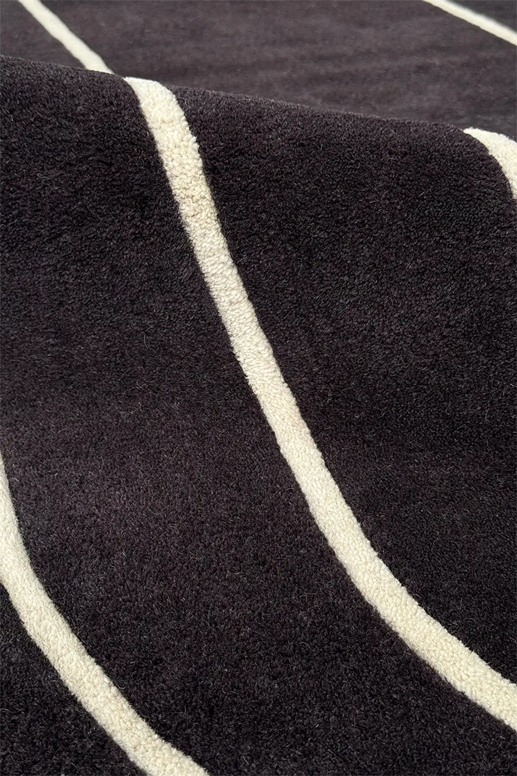 Close-up of geometric art deco rug, a black and white wool area rug in a bold curved stripe design