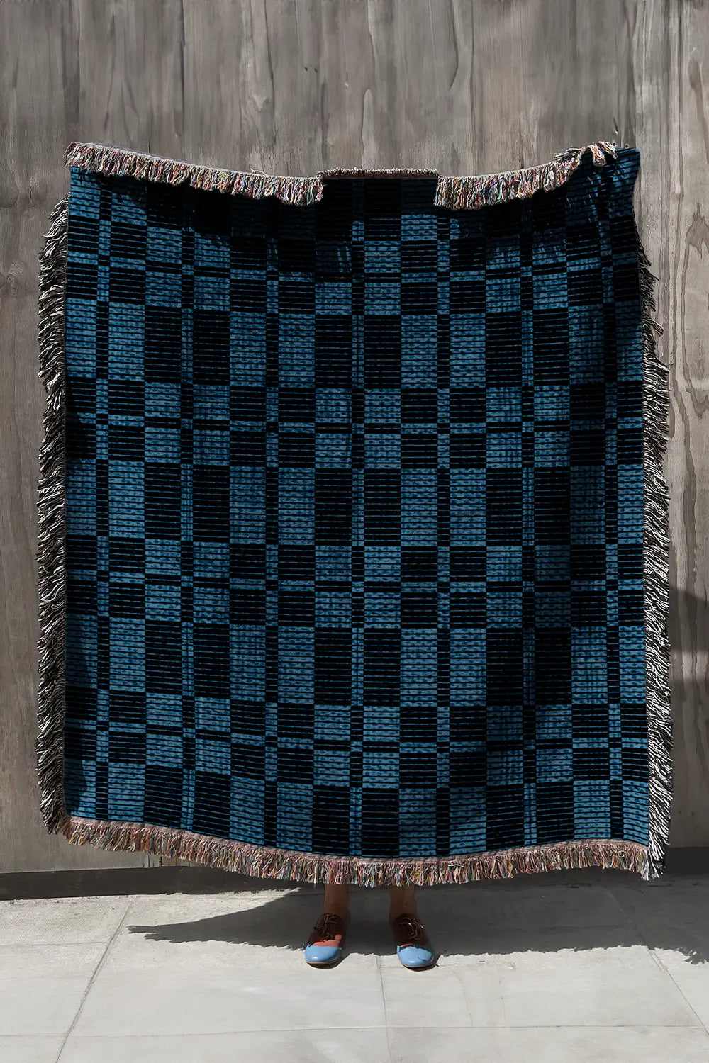 Blue and navy plaid woven throw blanket with fringe detailing.
