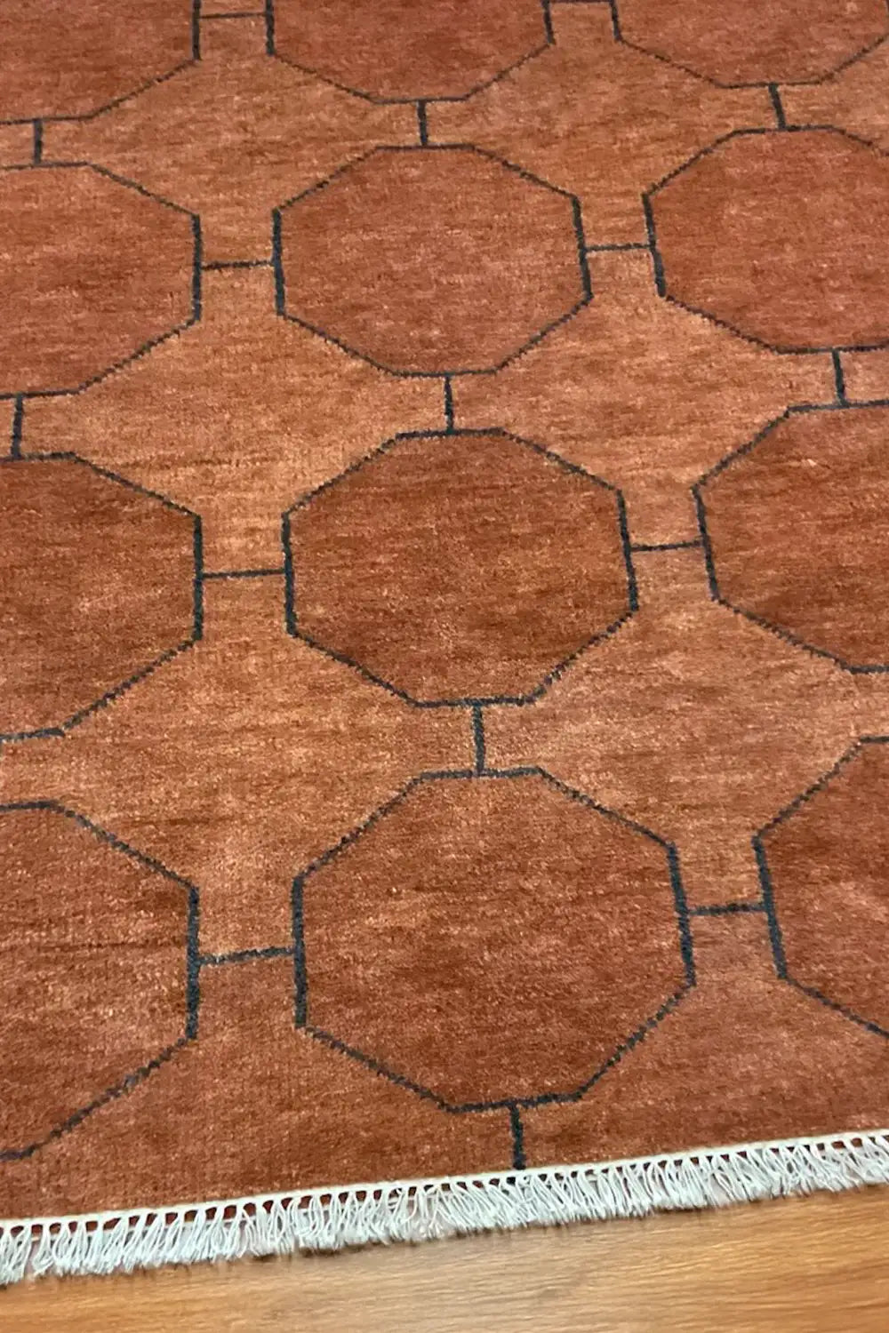 A closer view of the brown geometric rug, highlighting the precise handwoven details and subtle variations in wool texture.


