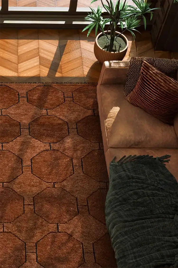 A beautifully lit interior space showcasing a brown geometric wool rug, herringbone wooden floors, and a cozy seating area with a neutral sofa and indoor greenery