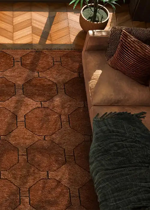 A warm brown wool area rug featuring an octagonal geometric pattern, styled with a neutral-toned sofa, textured pillows, and a dark green throw