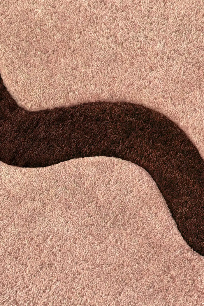 Detail of tan and dark brown tufted wool rug with high-low wavy texture and plush hand-sculpted pile