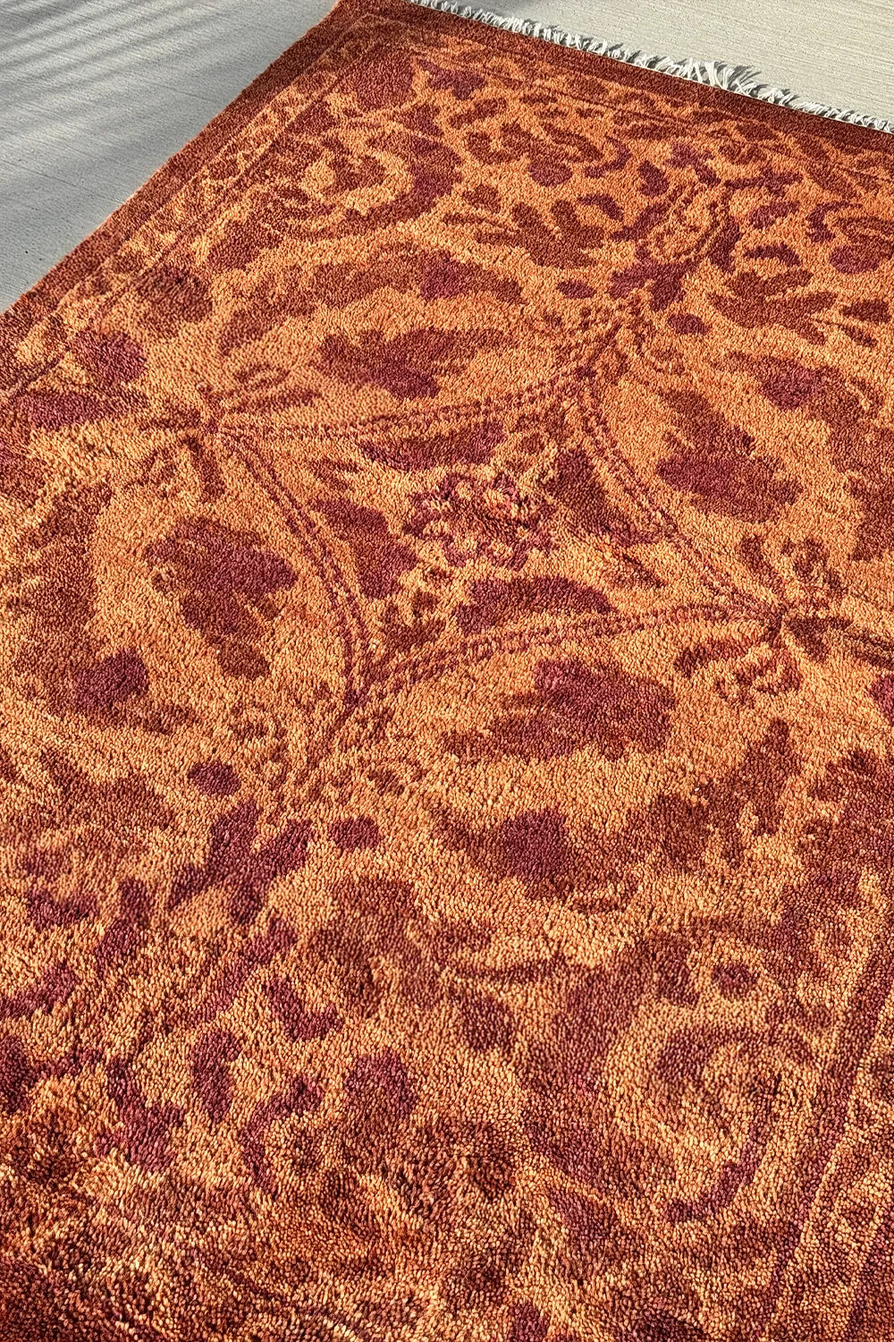 Vintage-inspired wool rug with a floral vine motif in rich terracotta tones