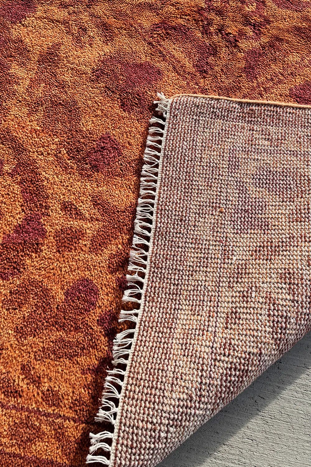 Handmade wool area rug with a detailed botanical pattern in rust and burnt orange.