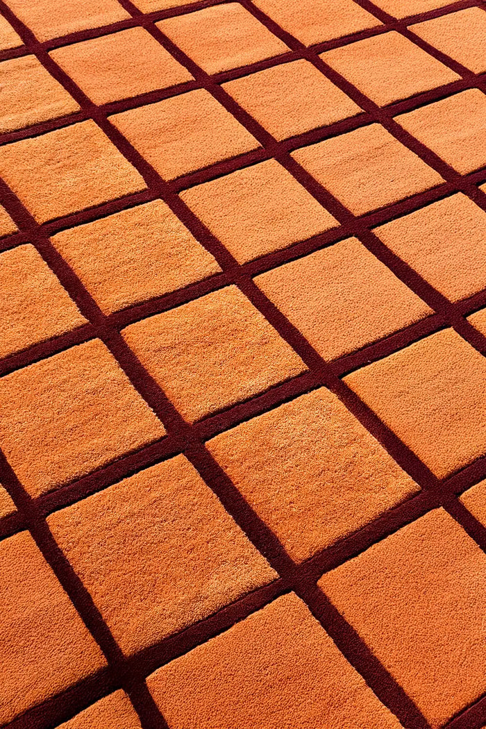 Mid century wool rug in terracotta and dark burgundy brown with raised grid design and sculpted carved pile
