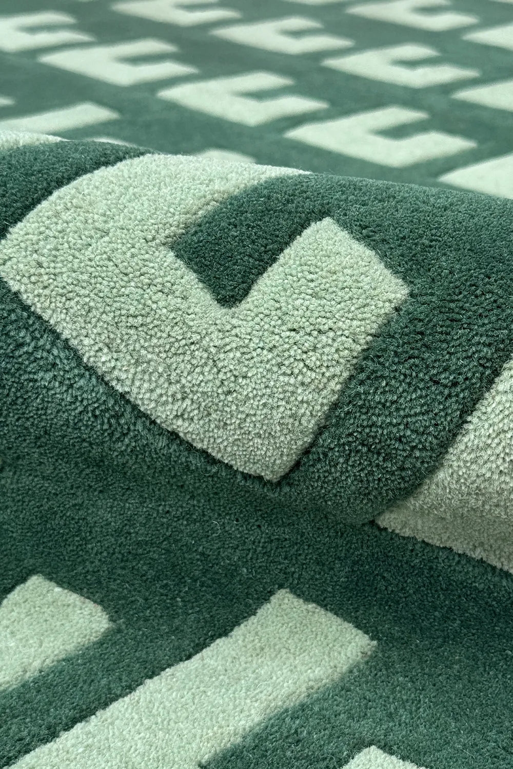Modern wool rug with stepped repeating green geometric design

