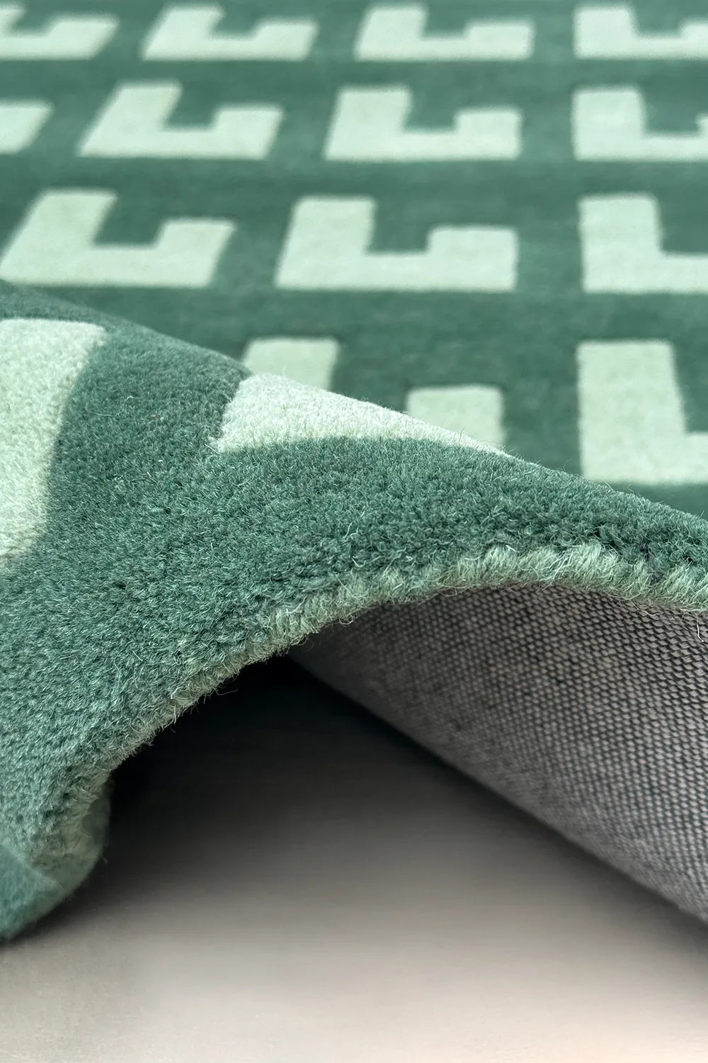 Modern geometric wool rug in sage and forest green tones

