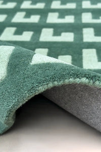 Midcentury modern geometric wool rug in sage and forest green tones

