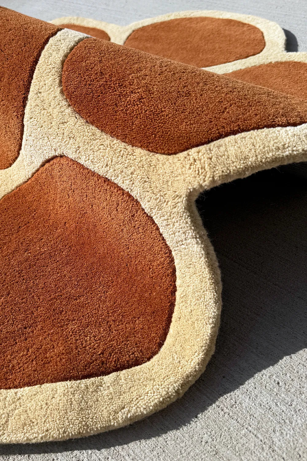 High pile wool texture of a terracotta  and cream novelty rug in an irregular shape for playful modern decor

