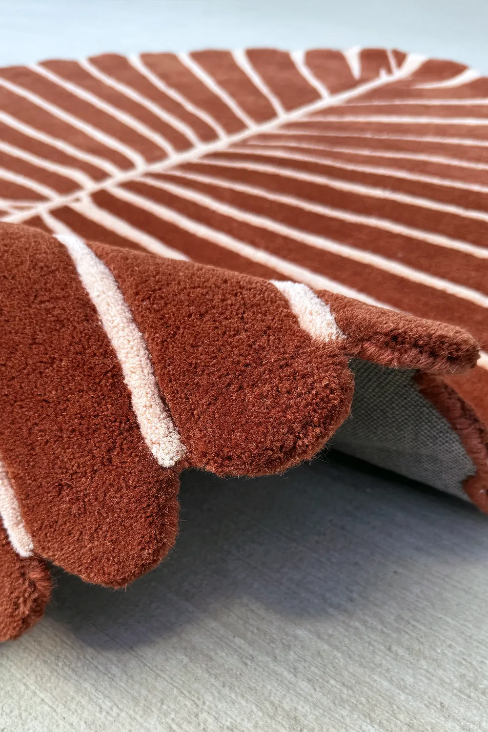 Scalloped edge of brown and cream wool rug – funky coastal-inspired rug with soft curved lines and botanical shape