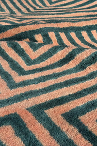 Close-up of plush peach and green shag rug with bold hand-knotted geometric stripes