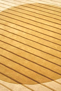 Modern tufted wool rug with carved golden circle over cream background and sculpted stripe texture