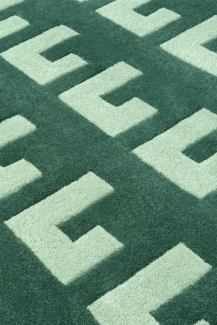 Geometric block pattern rug in green and mint, shown from low angle to highlight texture and symmetry
