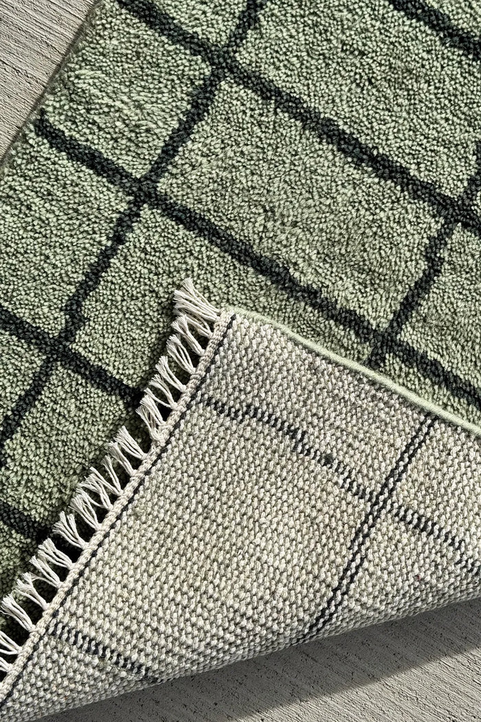 Close-up of the hand-knotted texture on a green modern wool area rug