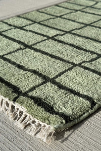 soft green wool area rug with modern minimalist black grid design perfect for japandi interiors