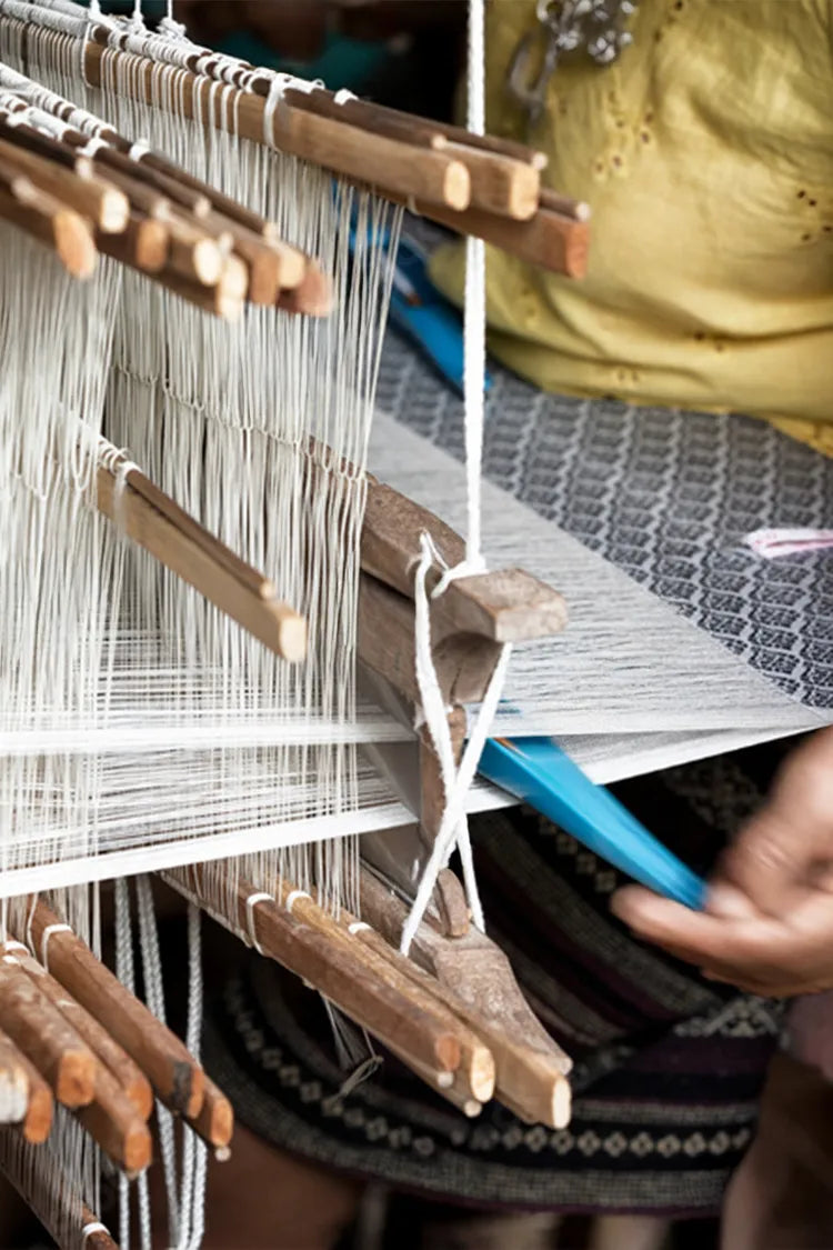 A detailed shot of an artisan's hand adjusting threads on a loom, emphasizing the precision and care in rug-making.