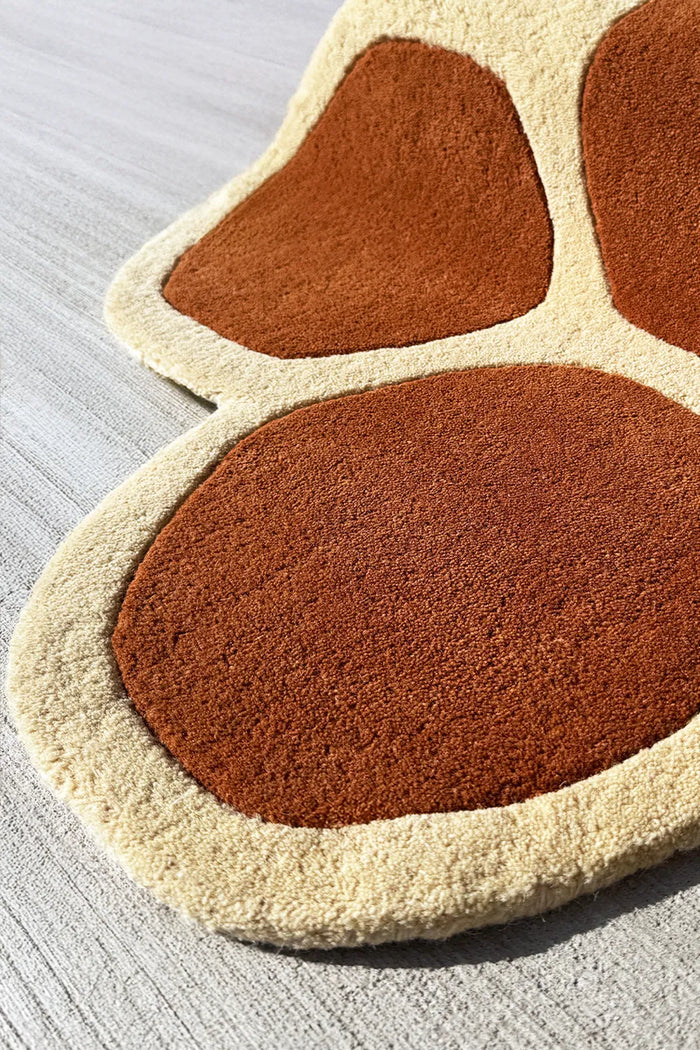 Close-up of scalloped edge on a hand tufted wool organic shaped retro rug with 70s boho flair