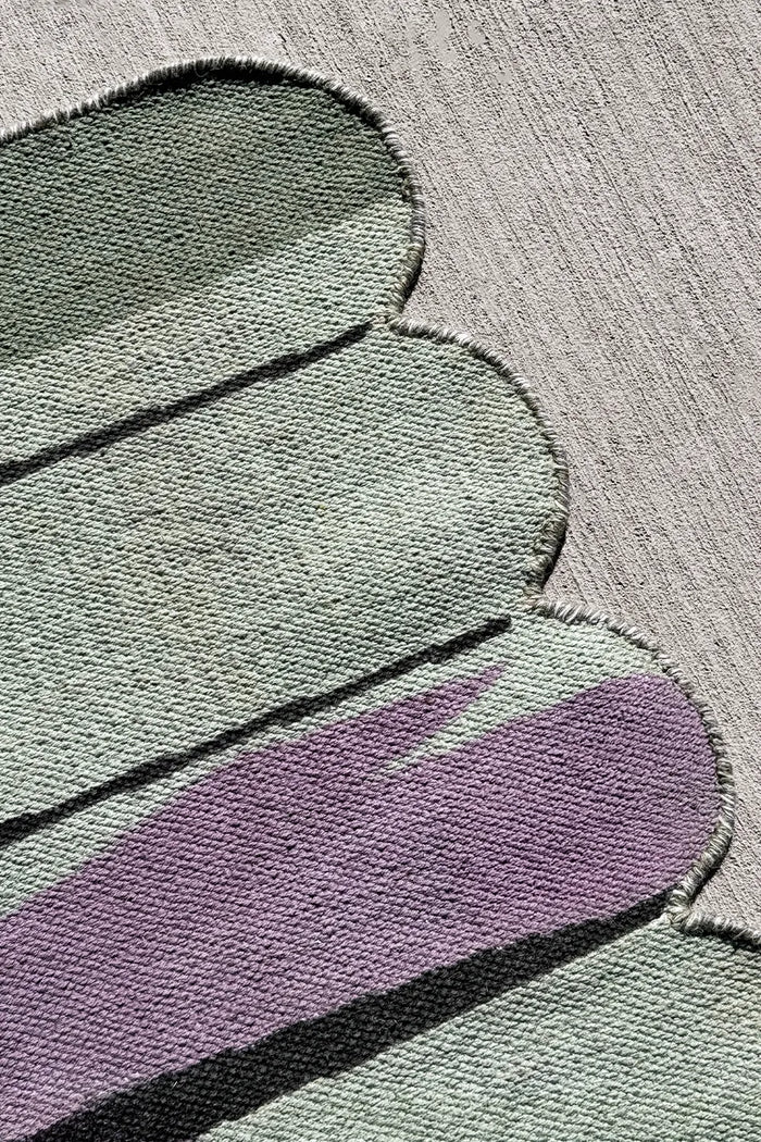 Close-up of purple, green, and black flatweave wool rug showing texture and curved color blocking