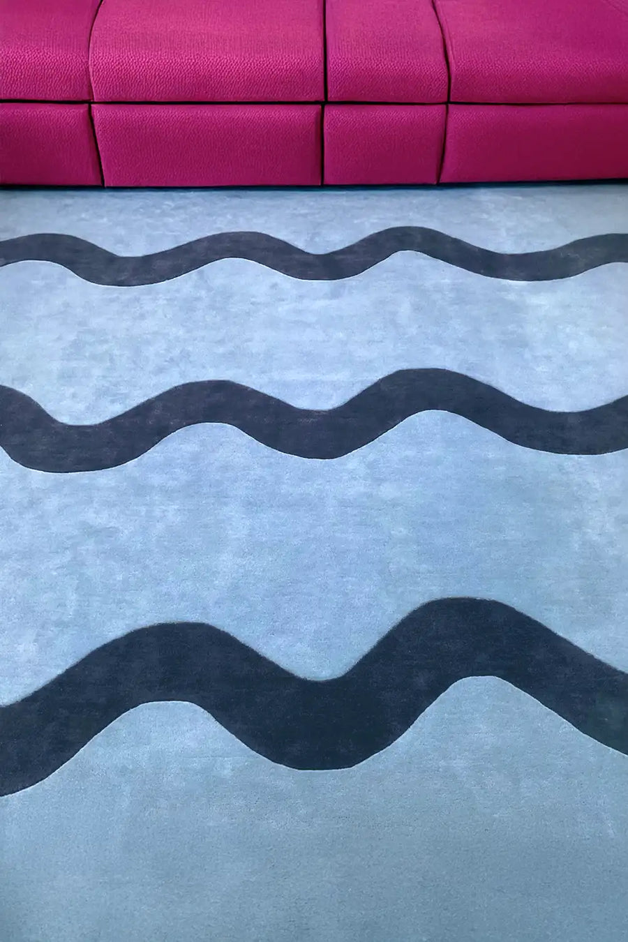 jubi light blue square wool area rug with dark blue unique wavy stripe in a modern living room with a dark pink couch