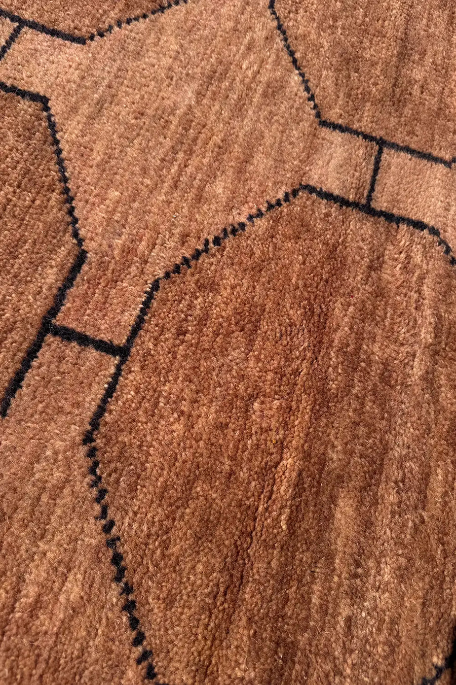 Close-up of brown octagonal pattern with black outlines on a geometric hand-knotted wool rug