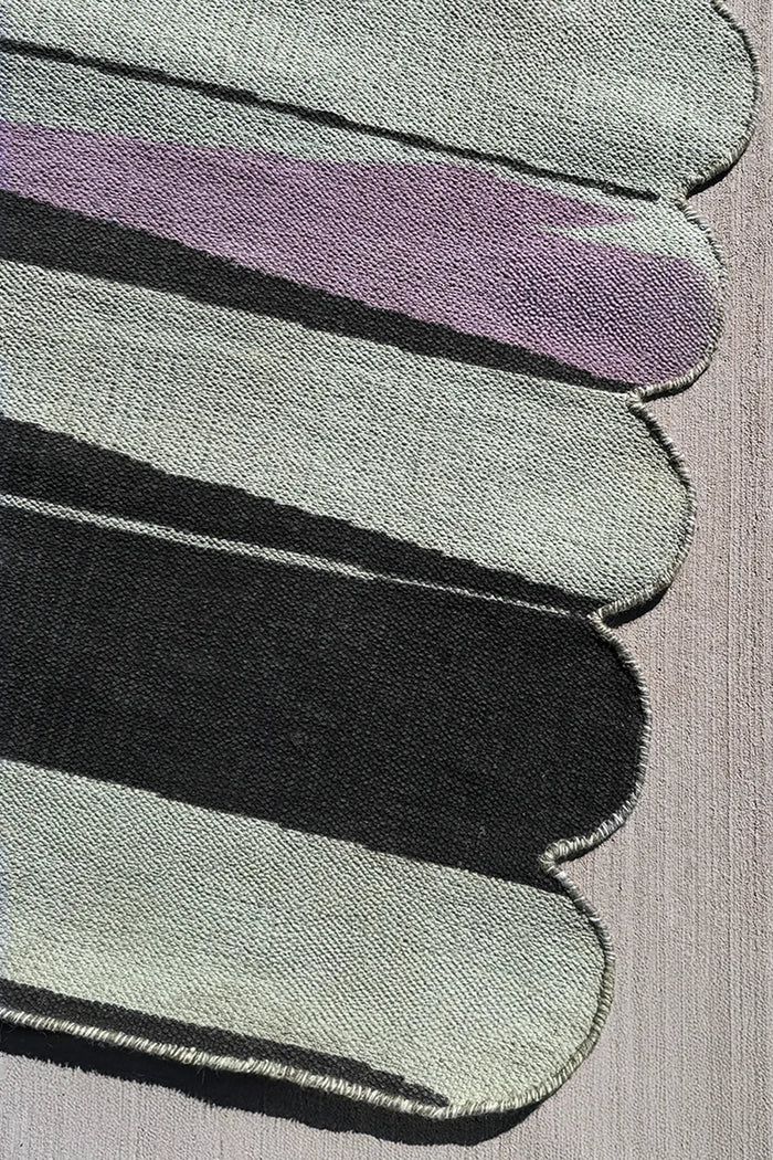Flatwoven green and purple wool rug with rounded edge detail and modern abstract striped design