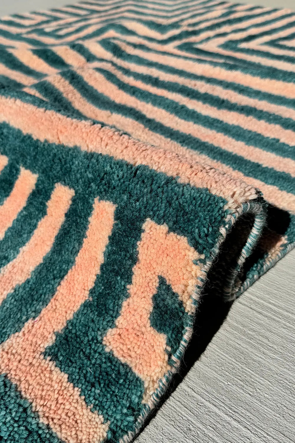Folded view of green and peach modern shag wool rug highlighting thick plush hand-tufted pile