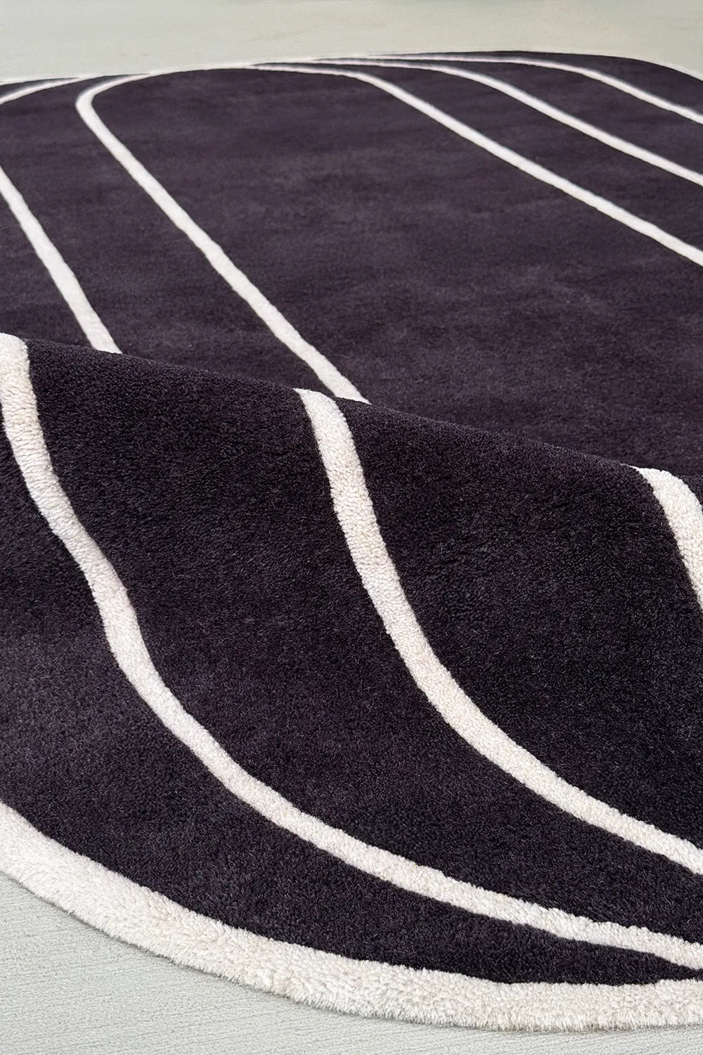 Black tufted rug with cream curved lines – luxury modern abstract rug for moody living rooms or dining areas

