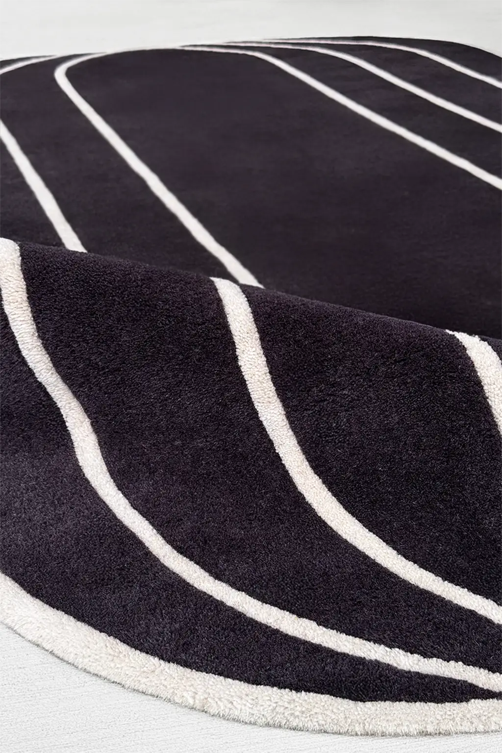 Black tufted rug with cream curved lines, great as a luxury modern abstract rug for moody living rooms or dining areas

