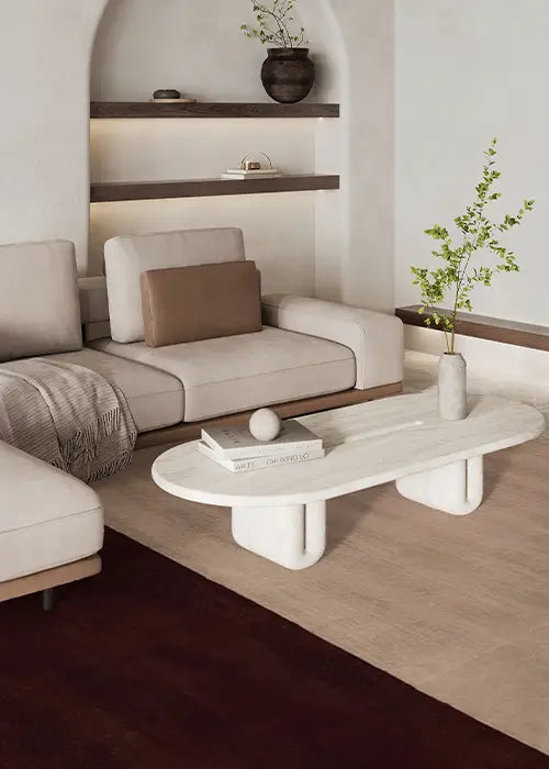 A contemporary living space featuring a neutral color palette, a beige and brown wool rug, a minimalist marble coffee table, and built-in shelves with warm accent lighting.