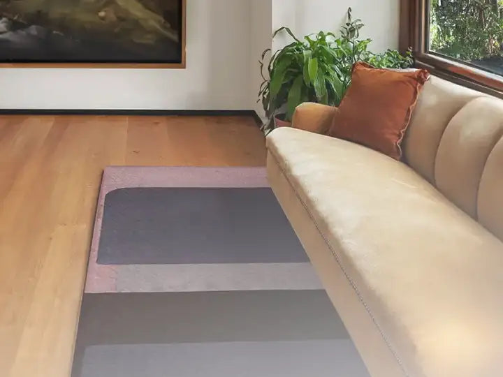 A living room with a light-colored sofa, a muted area rug, and a potted plant by the window, creating a warm and inviting space