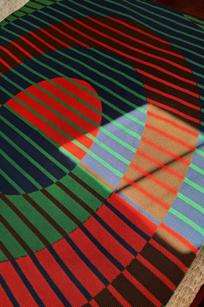 Modern striped knit blanket with concentric circles and vibrant color blocking.
