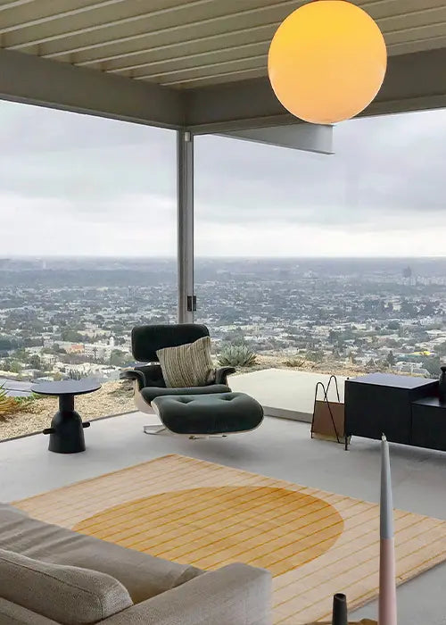 A warm yellow modern wool rug with a geometric circle pattern, adding a serene touch to a contemporary living space with panoramic city views.