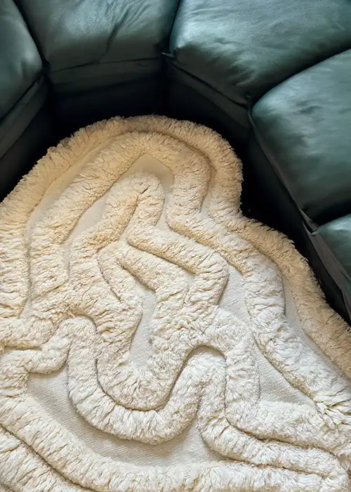 A cozy white shag version of the Rolling Tides rug styled in a living room nook with dark green furniture.