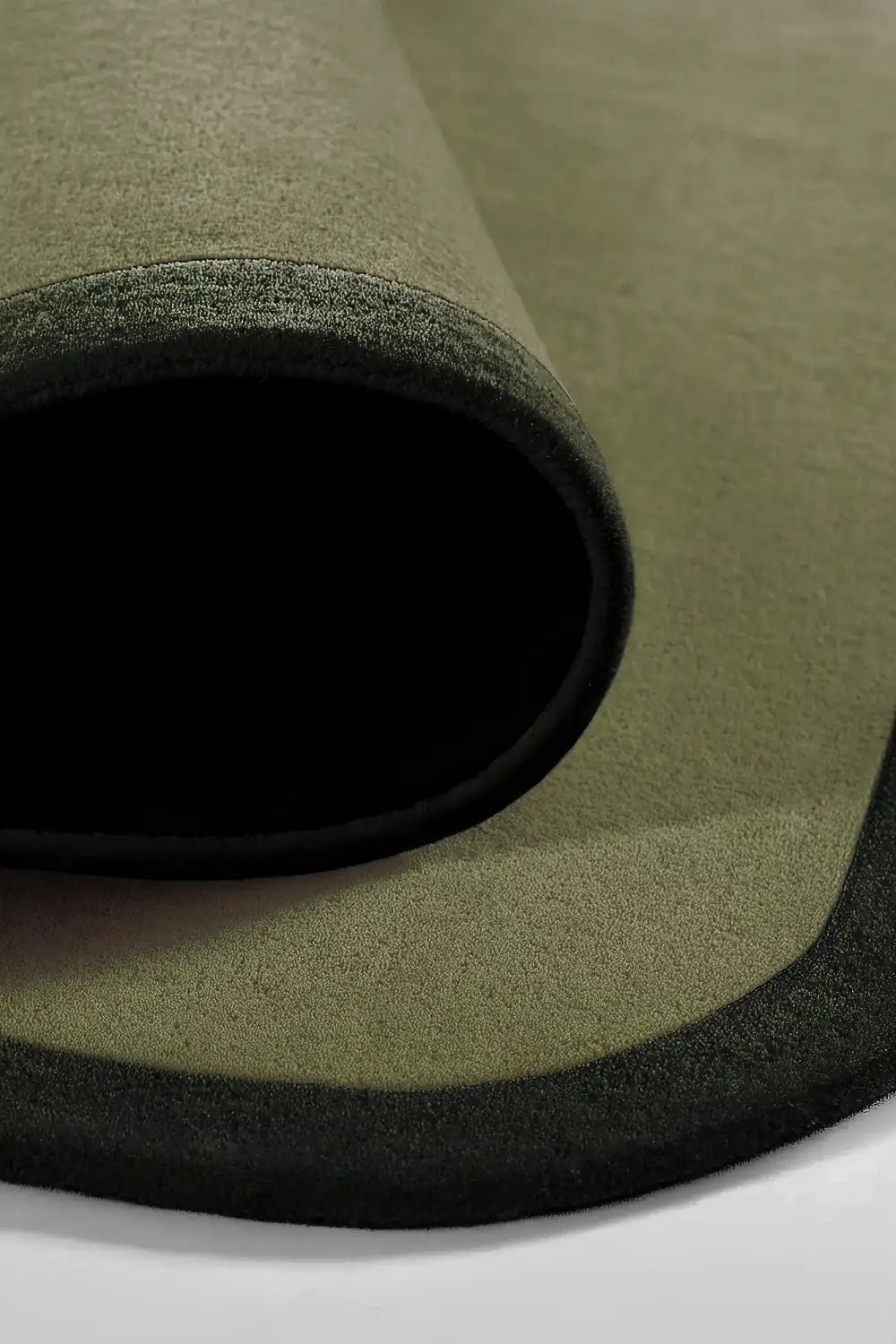 Square wool rug with rounded contour edges in modern green tones.
