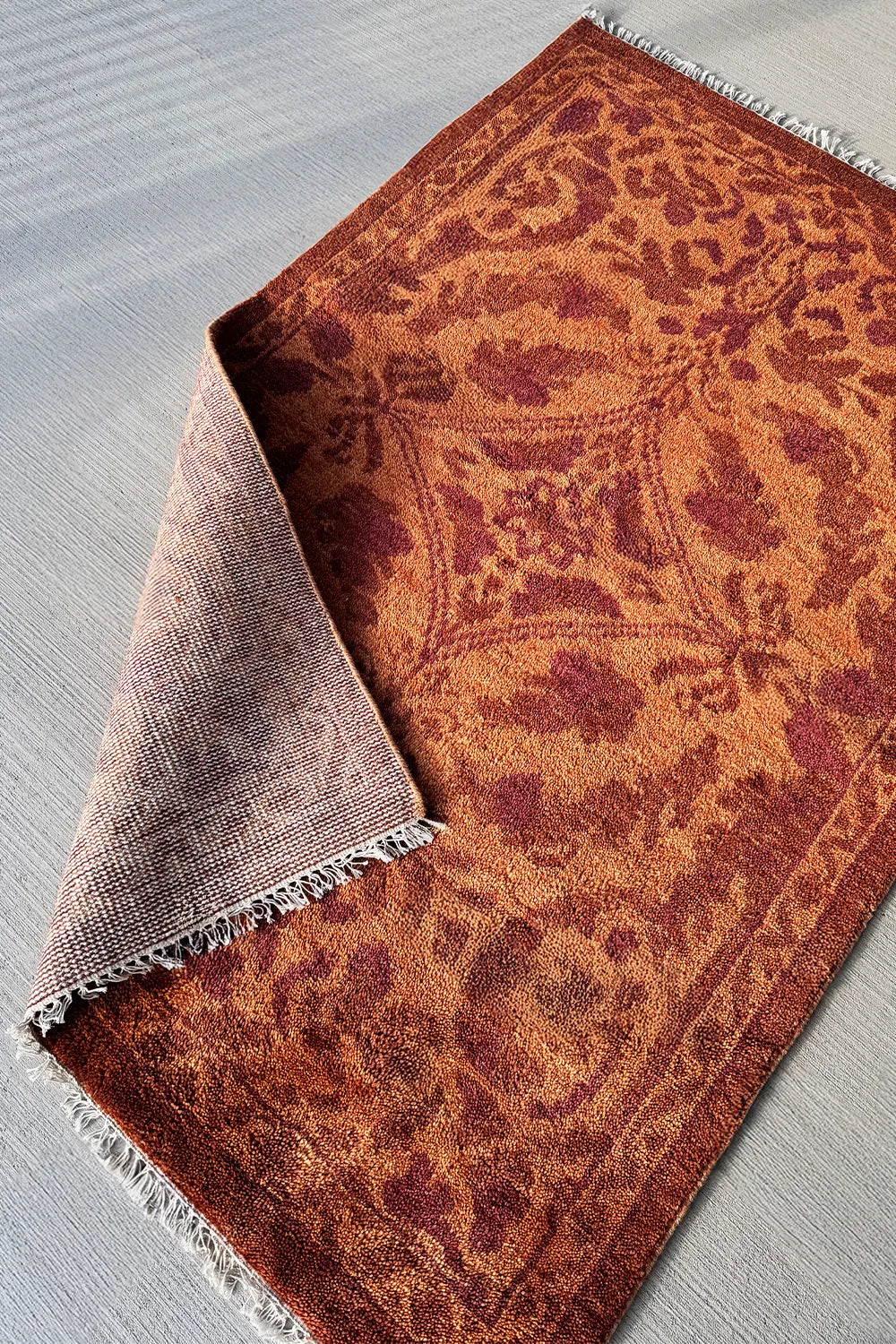 Warm terracotta and rust-colored rug with a textured hand-knotted finish