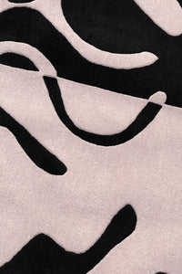 Close-up of black and white abstract curves on tufted wool rug