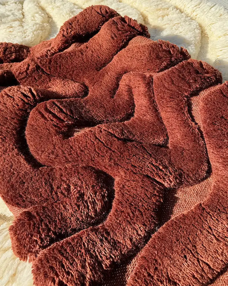 A close-up of a plush rust-colored shag rug with textured waves, emphasizing softness and comfort.