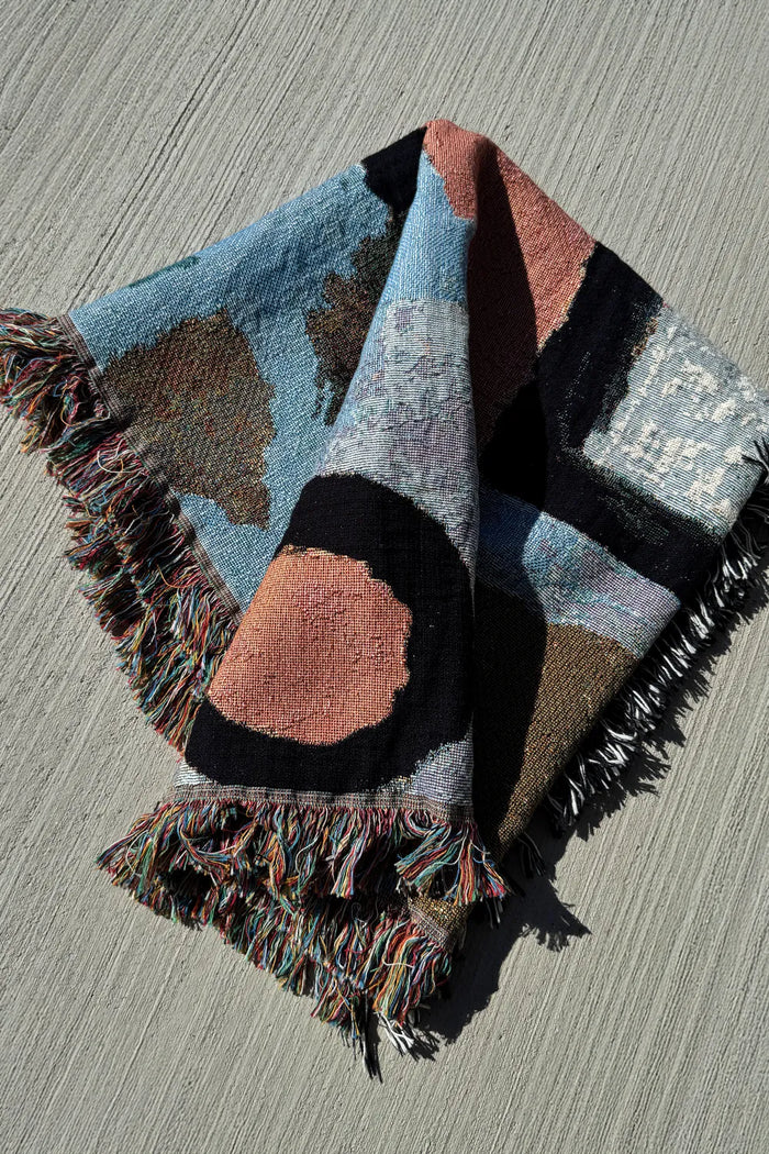 Textured cotton throw with folded layers and abstract shapes, ideal for use as a cozy couch throw or minimalist bed layer