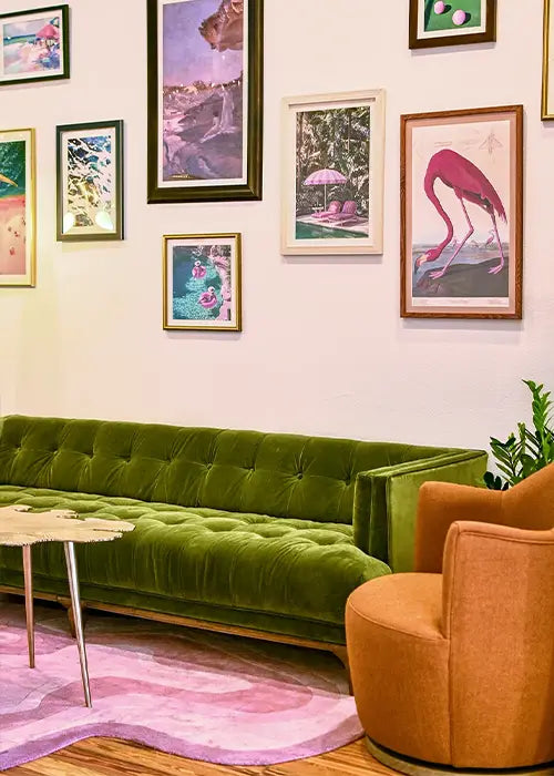 A custom pink-hued wool rug complementing an eclectic interior with an emerald green velvet sofa and vibrant framed art.