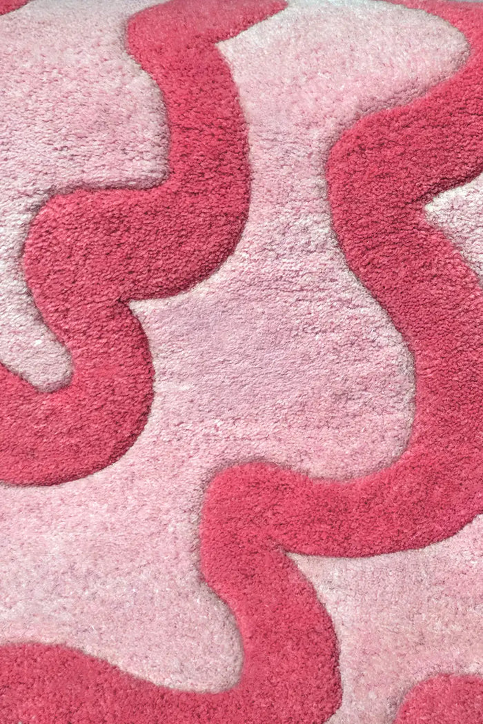Detailed texture view of wavy scalloped pink and red wool area rug for playful home decor