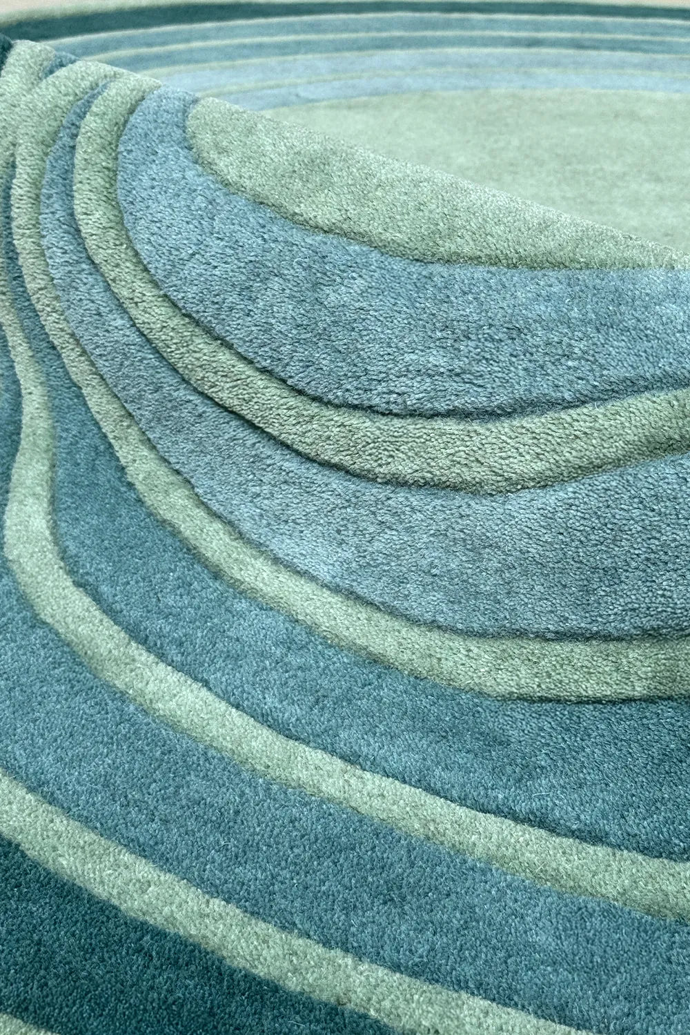 Green abstract shape rug with layered curves in teal and sage – funky modern wool rug for retro or coastal interiors

