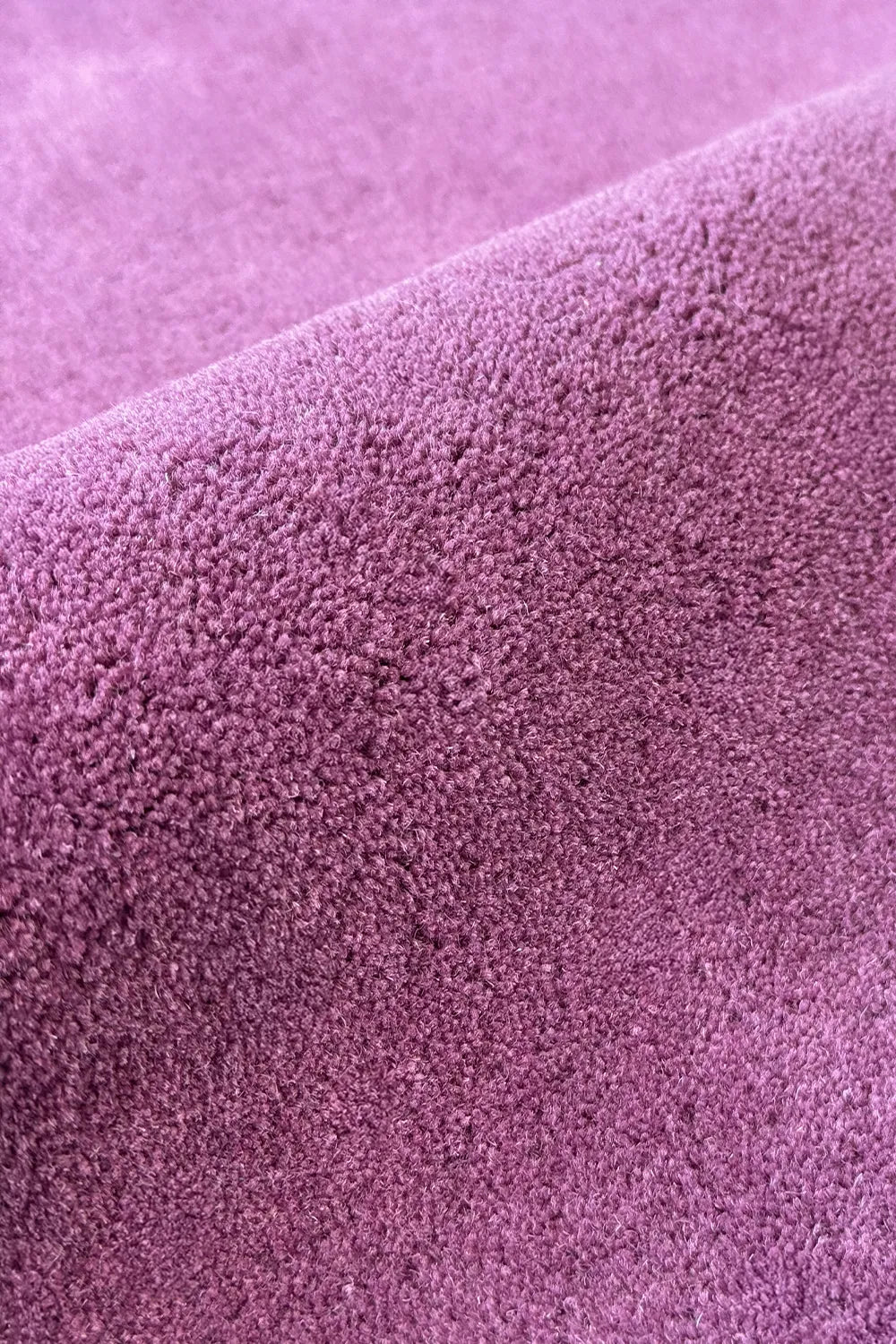 Close-up of plush pile on a soft, vibrant purple wool area rug 
