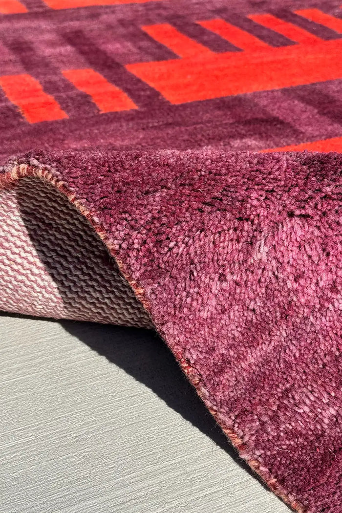 Handmade geometric Oushak rug with deep purple and fiery orange accents
