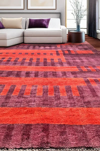Bold red and purple handmade wool rug in modern living room setting with white sectional sofa