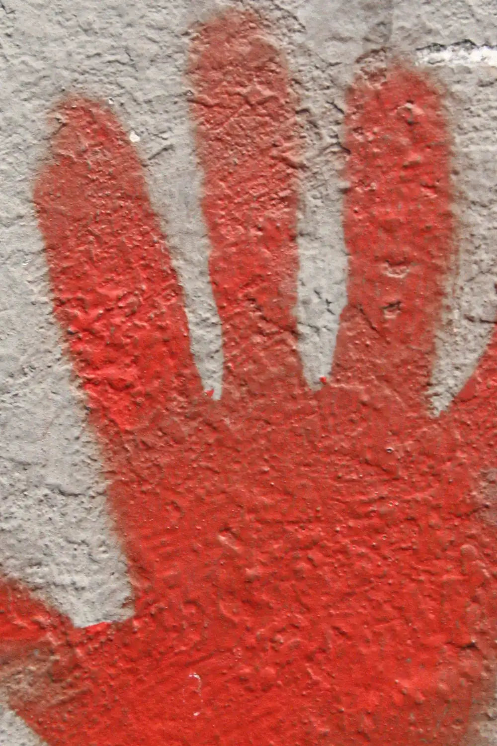 Abstract street art handprint in striking red on neutral gray
