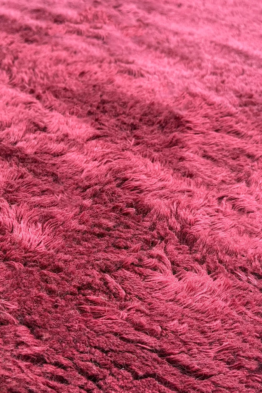 Close-up of soft red shag rug surface showing thick plush wool fibers and handcrafted high-pile finish