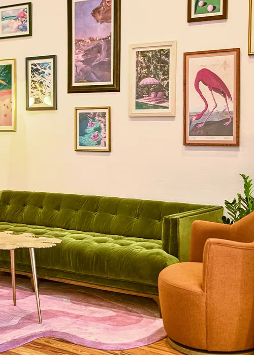 Stylish interior showcasing a green velvet sofa, playful gallery wall, and a pastel pink Jubi rug, blending vintage charm with contemporary design.