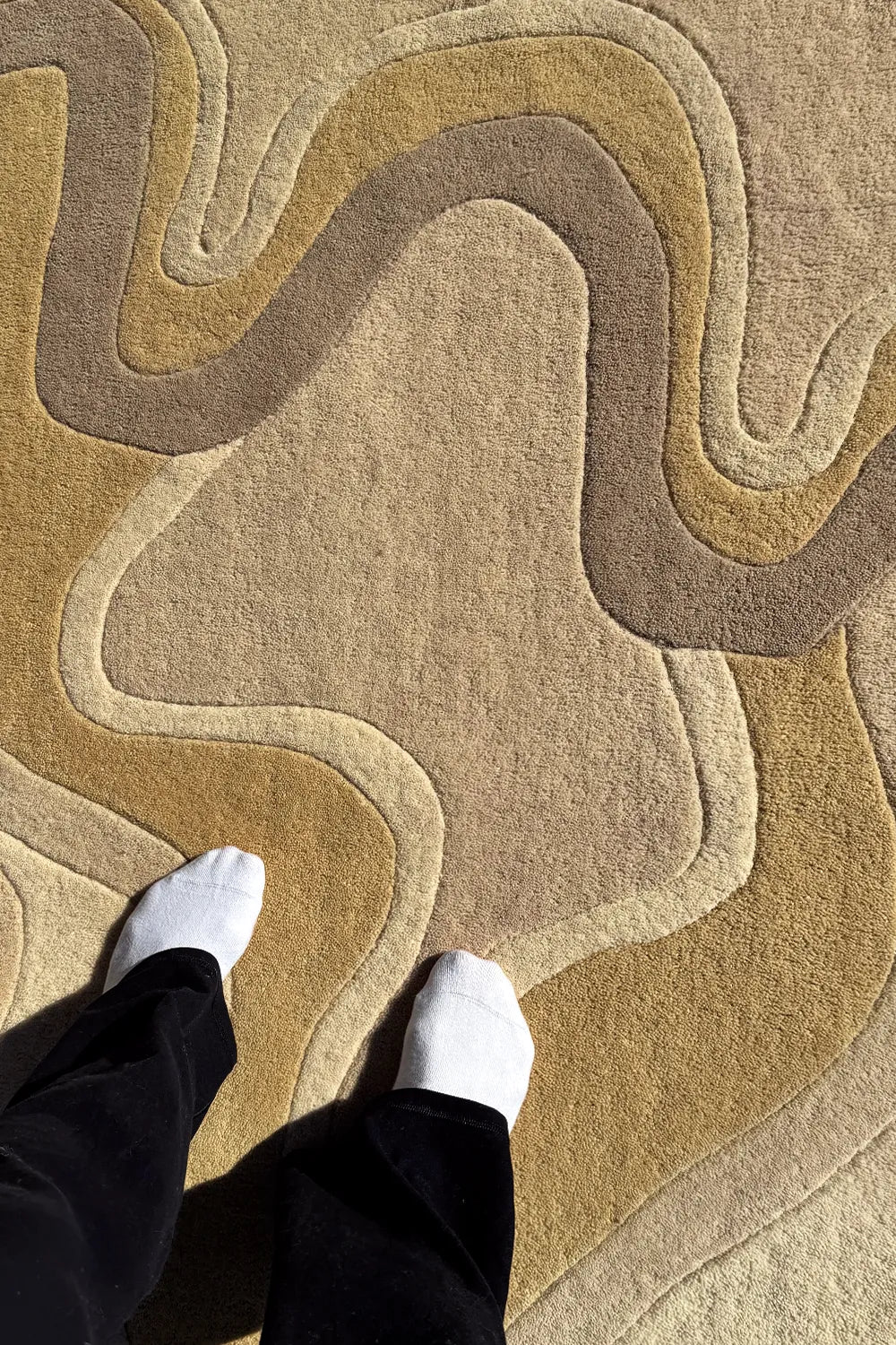 Modern organic wool rug with fluid wave pattern in tan and brown shades

