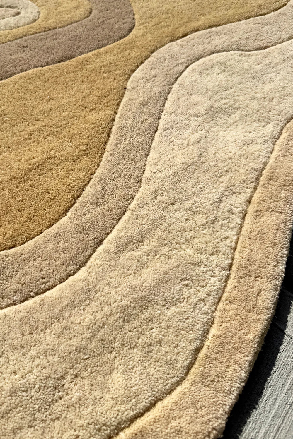 Sculpted-edge area rug with layered contours in warm, earthy neutrals
